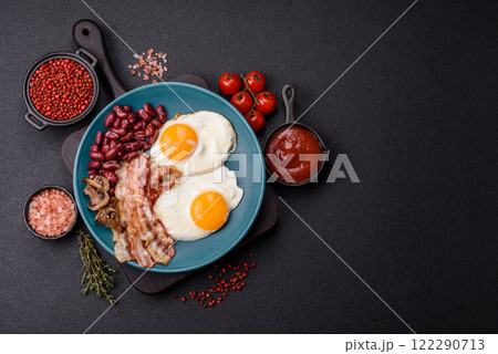 English breakfast with fried eggs, bacon, beans, tomatoes, spices and herbs 122290713