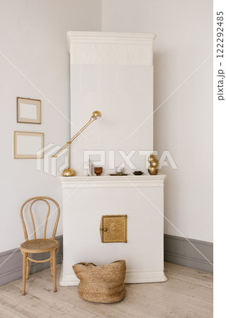 Corner of living room with white stove, chair and straw basket Corner of living room with white stove, chair and straw basket 122292485