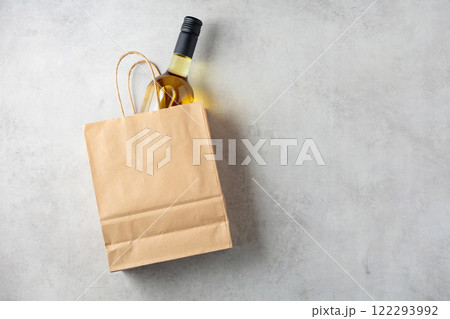 Bottle of white wine in a paper bag on a white marble background. 122293992
