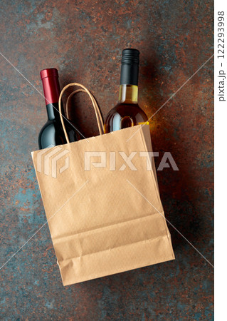 Bottles of red and white wine in a paper bag on a rusty background. Bottles of red and white wine in a paper bag on a rusty background. 122293998