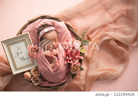 ニューボーンフォト_おくるみに包まれて幸せそうに新生児微笑を見せてすやすや眠る生まれたての赤ちゃん 122294426