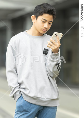 街並みでスマホを見る少年 122294809