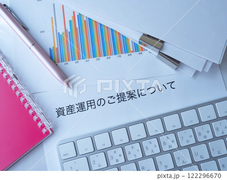 テーブルに置かれたグラフと書類とキーボードと手帳 122296670