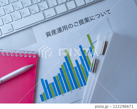 テーブルに置かれたグラフと書類とキーボードと手帳 122296671