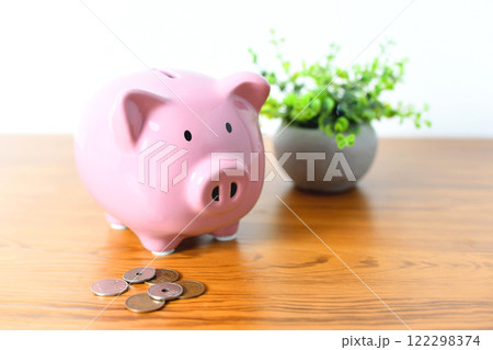 机に置かれた豚の貯金箱と硬貨のイメージ 机に置かれた豚の貯金箱と硬貨のイメージ 122298374