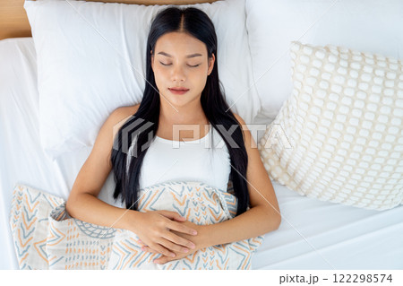 Top view beautiful Asian woman lie and sleep on bed with white pillow and express relax happiness. Top view beautiful Asian woman lie and sleep on bed with white pillow and express relax happiness. 122298574