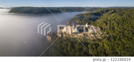 Majestic chateau de Castelnaud rises above misty Dordogne valley during sunrise, revealing its Majestic chateau de Castelnaud rises above misty Dordogne valley during sunrise, revealing its 122298834