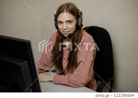 A happy call center agent working on a support hotline in the office. The call center operator is talking to the customer. Close-up. 122298884