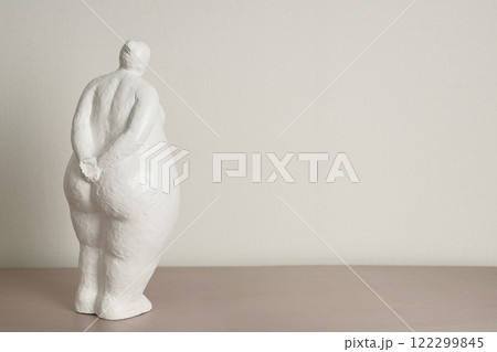 Figure of shy white clay woman looking at blank white wall 122299845