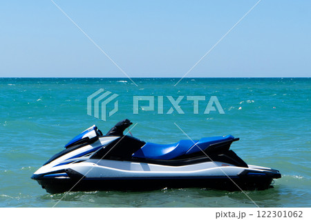 Blue sea and a jet ski floating on the sea. Water scooter is in the blue sea. Blue sea and a jet ski floating on the sea. Water scooter is in the blue sea. 122301062