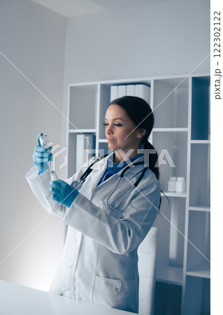 In a modern medical office, a dedicated female doctor prepares a syringe, prioritizing safety, cleanliness, and hygiene to ensure a positive outcome for her patients during the procedure 122302122