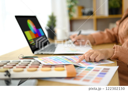 Creative woman selecting color palettes and working with design tools on a laptop. Creative woman selecting color palettes and working with design tools on a laptop. 122302130