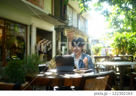 Excited man looking at his digital tablet and celebrating a success in an outdoor cafe Excited man looking at his digital tablet and celebrating a success in an outdoor cafe 122302163