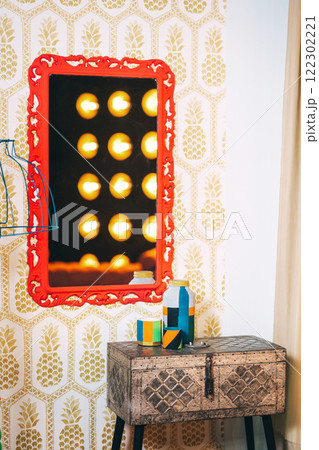 iron box on wooden legs with red frame on the wall and lamp. photo zone with mirror and table 122302221