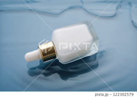 Bottle with white moisturizing serum in water on blue background. Bottle with white moisturizing serum in water on blue background. 122302579