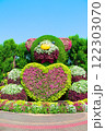 Bear with heart made from bushes of greenery and flowers. Petunias. Gardening, garden with floral design indicating natural tourist attraction on sunny day. Valentine's Day, holiday, birthday, 122303070