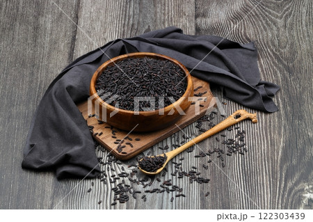 pile of black rice in a wooden bowl on a wooden table close-up 122303439
