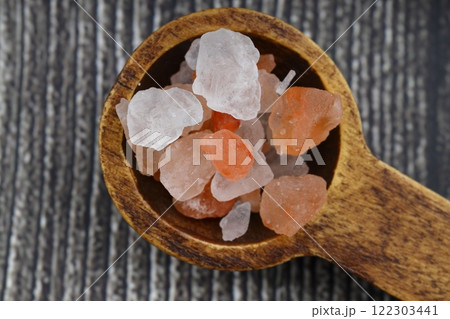 Pink Himalayan salt is poured with a wooden spoon. Himalaya salt on a dark background. Copy space. Macro Photography. Pink Himalayan salt is poured with a wooden spoon. Himalaya salt on a dark background. Copy space. Macro Photography. 122303441