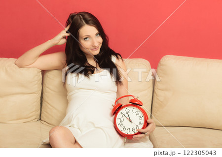Pregnant woman holding alarm clock 122305043