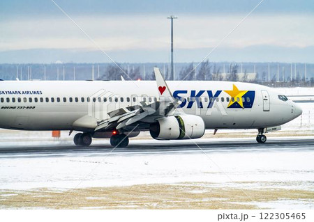 冬の新千歳空港　雪煙と着陸する飛行機　北海道千歳市　 122305465