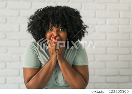 Laughing millennial African American woman with an afro hairstyle and good sense of humor smiling and laugh on brick wall at home background. Copy space. Happiness and good emotions concept Laughing millennial African American woman with an afro hairstyle and good sense of humor smiling and laugh on brick wall at home background. Copy space. Happiness and good emotions concept 122305509