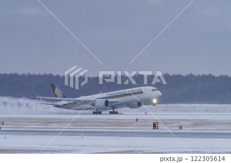 冬の新千歳空港　雪煙と着陸する飛行機　北海道千歳市　 122305614