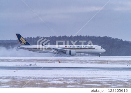冬の新千歳空港　雪煙と着陸する飛行機　北海道千歳市　 122305616
