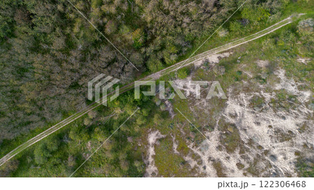 Aerial view of a grassy landscape with intersecting dirt paths, surrounded by scattered trees and open green fields, capturing a tranquil Aerial view of a grassy landscape with intersecting dirt paths, surrounded by scattered trees and open green fields, capturing a tranquil 122306468