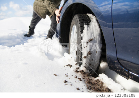 雪道でスタックした車を押す 122308109