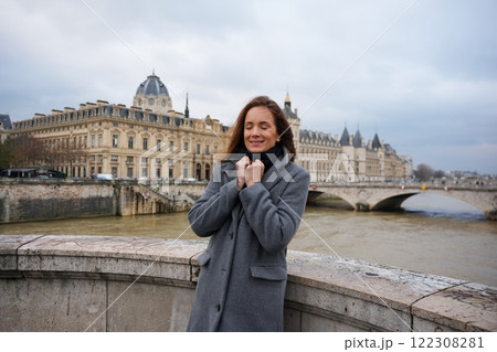 Woman Standing on Paris Bridge Overlooking Seine River and Historic Architecture 122308281