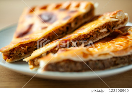 Closeup of traditional Russian meat pies showcasing flaky golden crusts and savory fillings on a plate 122308960