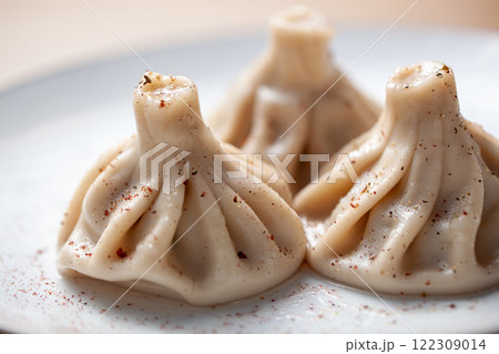 Traditional khinkali dumplings on a plate with pepper seasoning sprinkled on top and soft focus background Traditional khinkali dumplings on a plate with pepper seasoning sprinkled on top and soft focus background 122309014