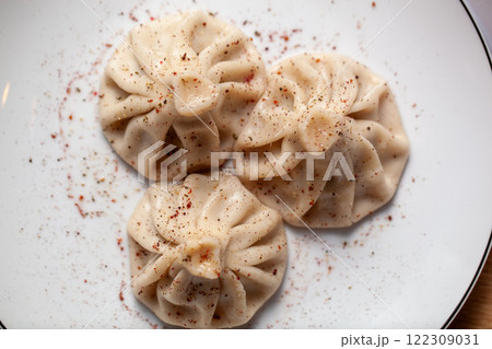 Top view of three traditional khinkali dumplings garnished with spices on a plate Top view of three traditional khinkali dumplings garnished with spices on a plate 122309031