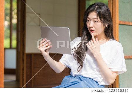 タブレット見て驚く若い女性 122310853