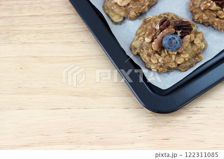 Homemade oat and banana cookie topping with blueberry, walnut and pecan on the oven tray, dessert for vegan Homemade oat and banana cookie topping with blueberry, walnut and pecan on the oven tray, dessert for vegan 122311085