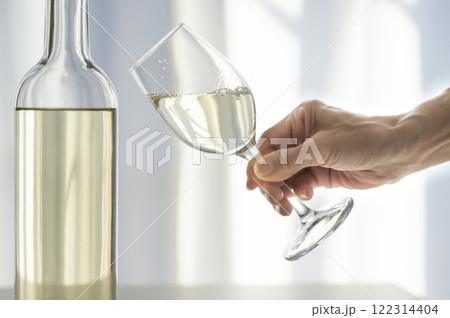 グラスに注がれた白ワインを持つ女性 122314404