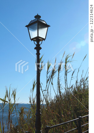 Lamp post against blue sunny sky near sea. Traditional objects of old town. Illumination of city, Liguria. Lamp post against blue sunny sky near sea. Traditional objects of old town. Illumination of city, Liguria. 122314624