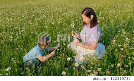 Mother And Son In Meadow Pick Flowers For Bouquet. Family Walk Spring. Happy Family Spending Time Together. Summer Landscape On Hill. Moves slowly. 122316735