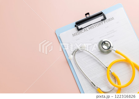 Doctor Day highlights a clipboard with a medical history form and yellow stethoscope on pink Doctor Day highlights a clipboard with a medical history form and yellow stethoscope on pink 122316826