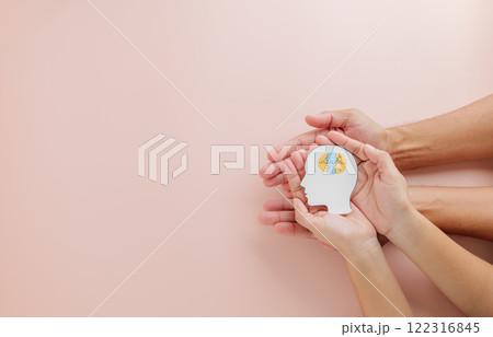 Hands of adult and child holding a brain jigsaw in a head paper cut Hands of adult and child holding a brain jigsaw in a head paper cut 122316845