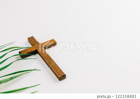 Wooden cross and green palm fronds on white background. Simple, minimalist design. Perfect for religious celebrations. 122316881