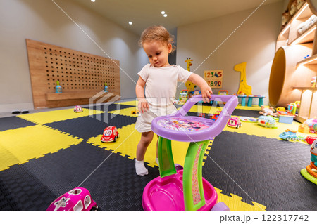 Toddler playing with toys in vibrant and modern playroom. Concept of indoor fun and creativity Toddler playing with toys in vibrant and modern playroom. Concept of indoor fun and creativity 122317742