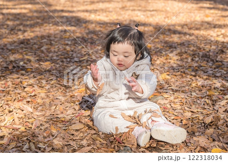 【落ち葉で敷き詰められた冬の公園で遊ぶ1歳児 座る】 【落ち葉で敷き詰められた冬の公園で遊ぶ1歳児 座る】 122318034