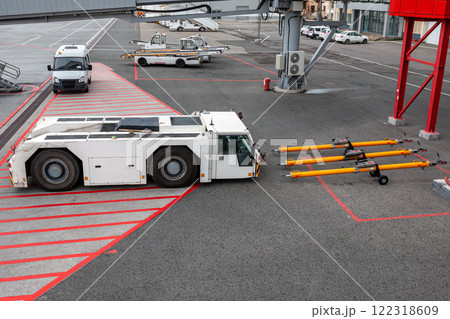 Aircraft tow tractor near towbars, self-propelled conveyor belt loaders and minibus at the airport apron Aircraft tow tractor near towbars, self-propelled conveyor belt loaders and minibus at the airport apron 122318609