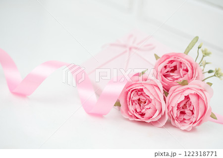 Three pink roses with ribbon and giftbox on the white table Three pink roses with ribbon and giftbox on the white table 122318771