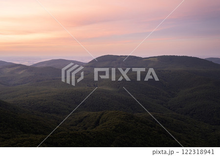 Green forested hilly landscape with purple skies during early morning sunrise, Slovakia, Europe Green forested hilly landscape with purple skies during early morning sunrise, Slovakia, Europe 122318941