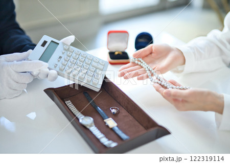 貴金属を査定する買取専門業者とミドル女性の手元 122319114