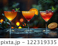 Still life of three bright yellow and red drinks in different glasses on a dark background of the bar counter. 122319335