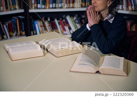 A focused individual sitting at a library desk with open books, symbolizing learning and research in a serene and knowledgeable environment. Reflects concepts like education, concentration, and A focused individual sitting at a library desk with open books, symbolizing learning and research in a serene and knowledgeable environment. Reflects concepts like education, concentration, and 122320360