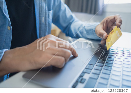 Man holding credit card while using laptop, shopping online, buying on internet. e-commerce e-banking service. 122320367